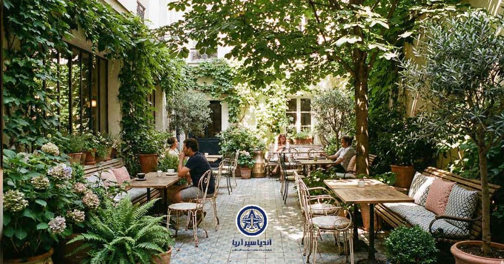 حیاط خلوت دنج و گل‌کاری شده هتل هانریت با میز و صندلی‌های قدیمی